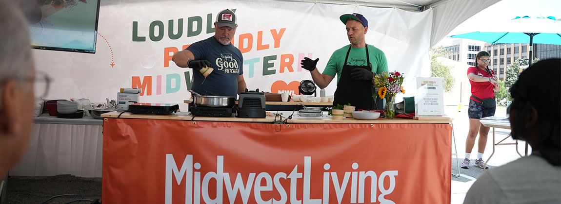 Two men behind a table cooking